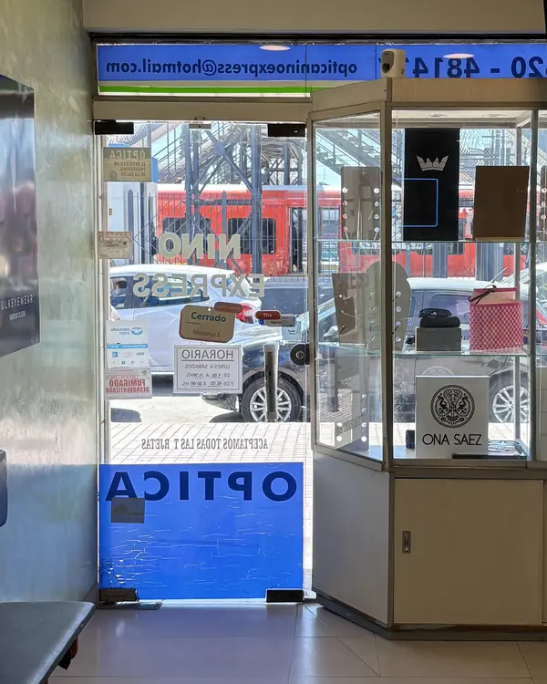Desde adentro del local, por la puerta de vidrio se ve la estación de Grand Bourg con un tren rojo parado